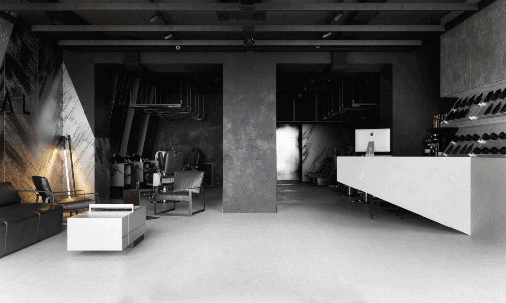 grey, black & white style barbershop with geometric counter with apple computer & leather seating area 